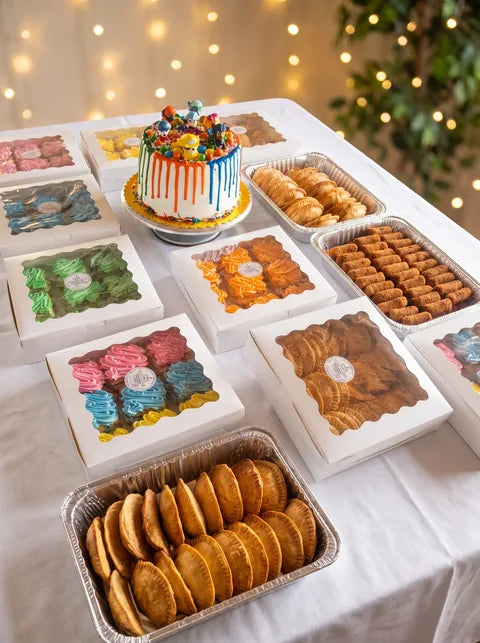 Mesa con cajas de dulces de colores, cake con goteo y bandejas para fiesta | Will & Mill Miami